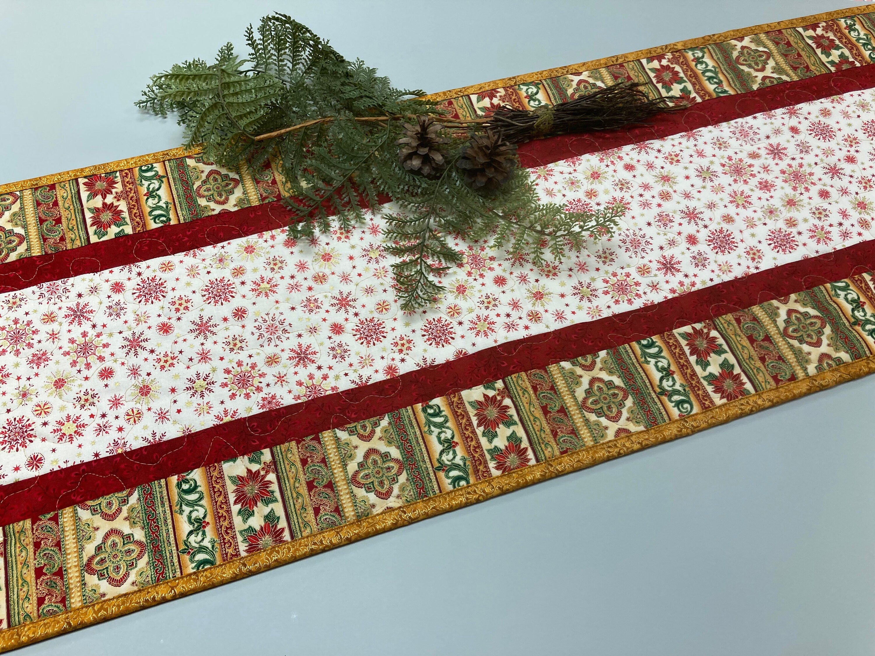 Christmas and poinsettia table runner with holly and wood roses and pine cones. Lots of gold and machine quilted in gold outlet 48”x14”